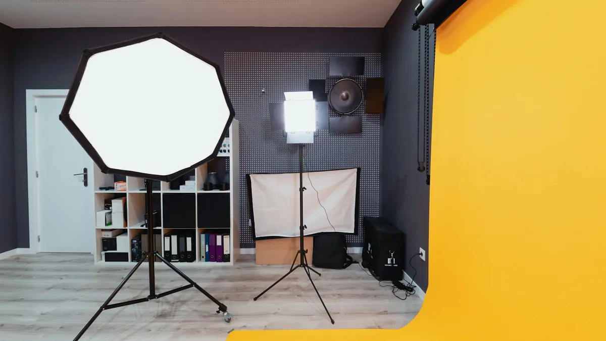 Estúdio fotográfico com uma softbox octogonal num tripé, um painel de luz contínua e um fundo de papel amarelo em curva até ao chão